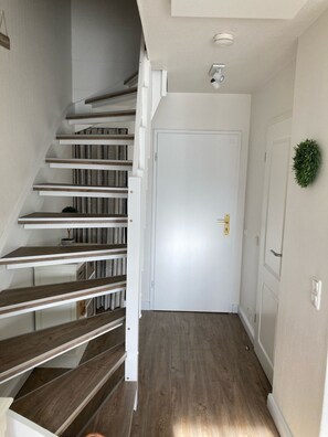 A staircase with wooden steps and white railings leading to a white door with a brass handle. - Ankerplatz - Your cozy anchorage in Westerland on Sylt for a (Sylt)