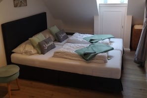 A bedroom with a bed, pillows, a bedside table, and a window. - Ankerplatz - Your cozy anchorage in Westerland on Sylt for a (Sylt)