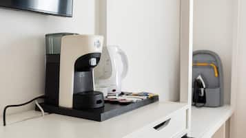 Een koffiezetapparaat en een waterdispenser op een wit aanrecht, met een televisie erboven bevestigd.