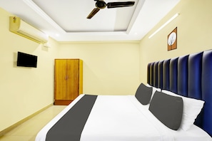 A hotel room with a bed, a wardrobe, a television, a ceiling fan, and a wall clock. - Hotel O Padmavathi Puram  (Tirupati)