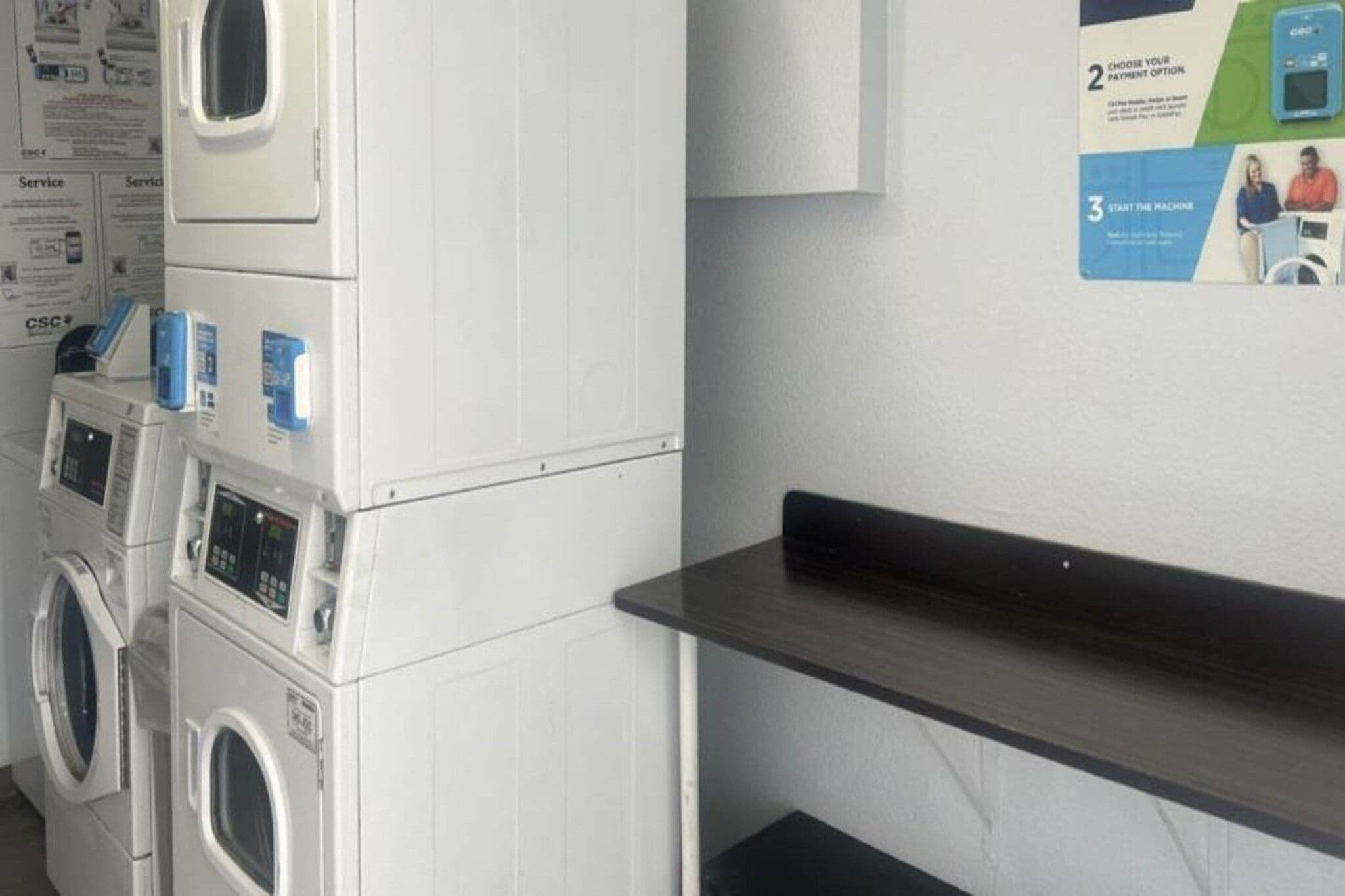 Ein Waschraum mit gestapelten Waschmaschinen und einem an der Wand befestigten Wäscheständer.