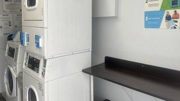 A laundry area with stacked washing machines and a wall-mounted drying rack.