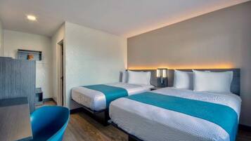 Habitación de hotel con dos camas, un escritorio y una silla.