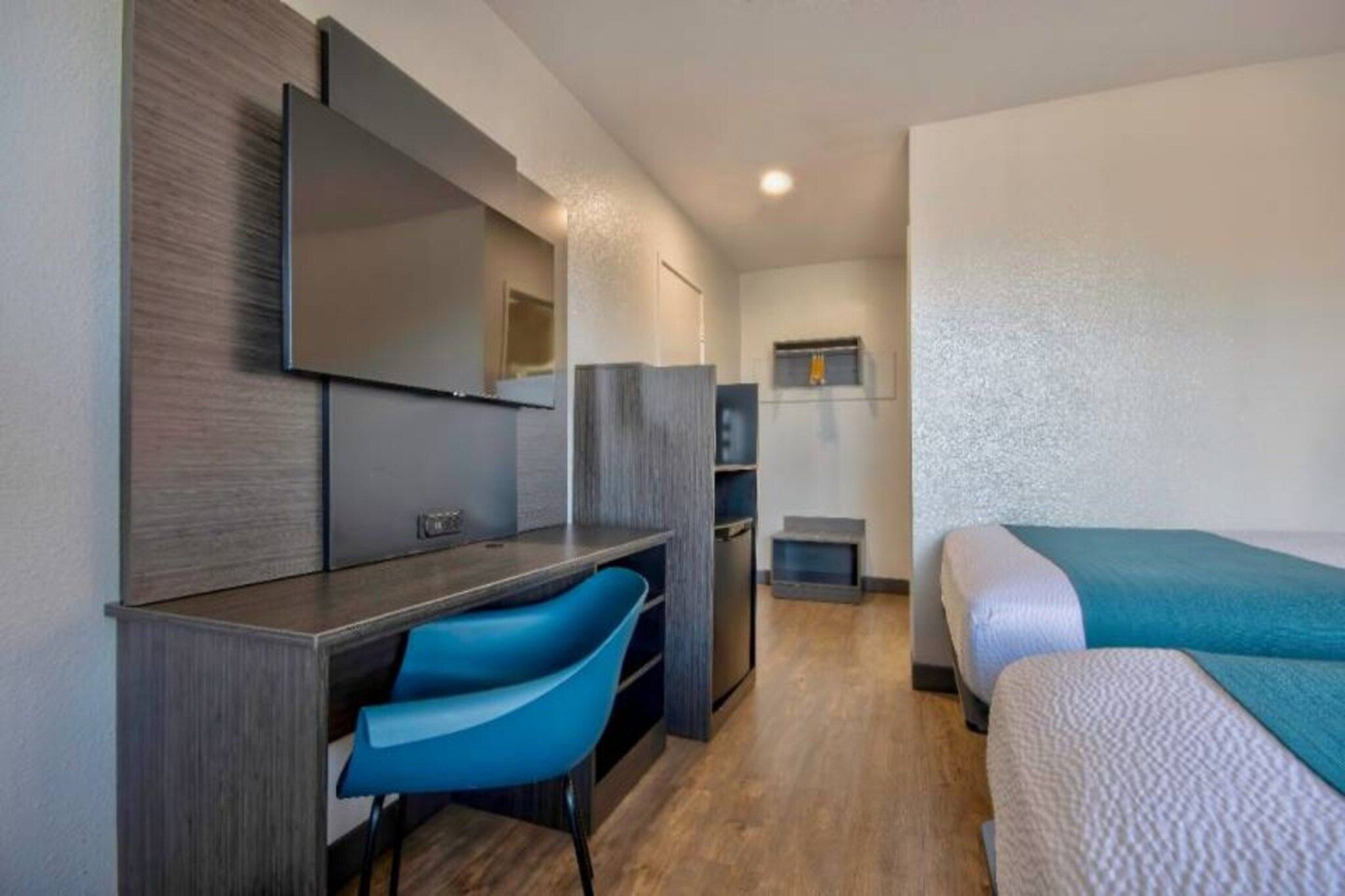 A hotel room with a bed, a desk, a chair, a television, and a wardrobe.