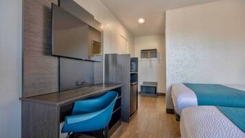 A hotel room with a bed, a desk, a chair, a television, and a wardrobe.