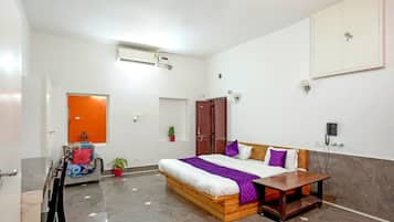 Un dormitorio con cama, mesita de noche, armario y una pequeña mesa con silla.