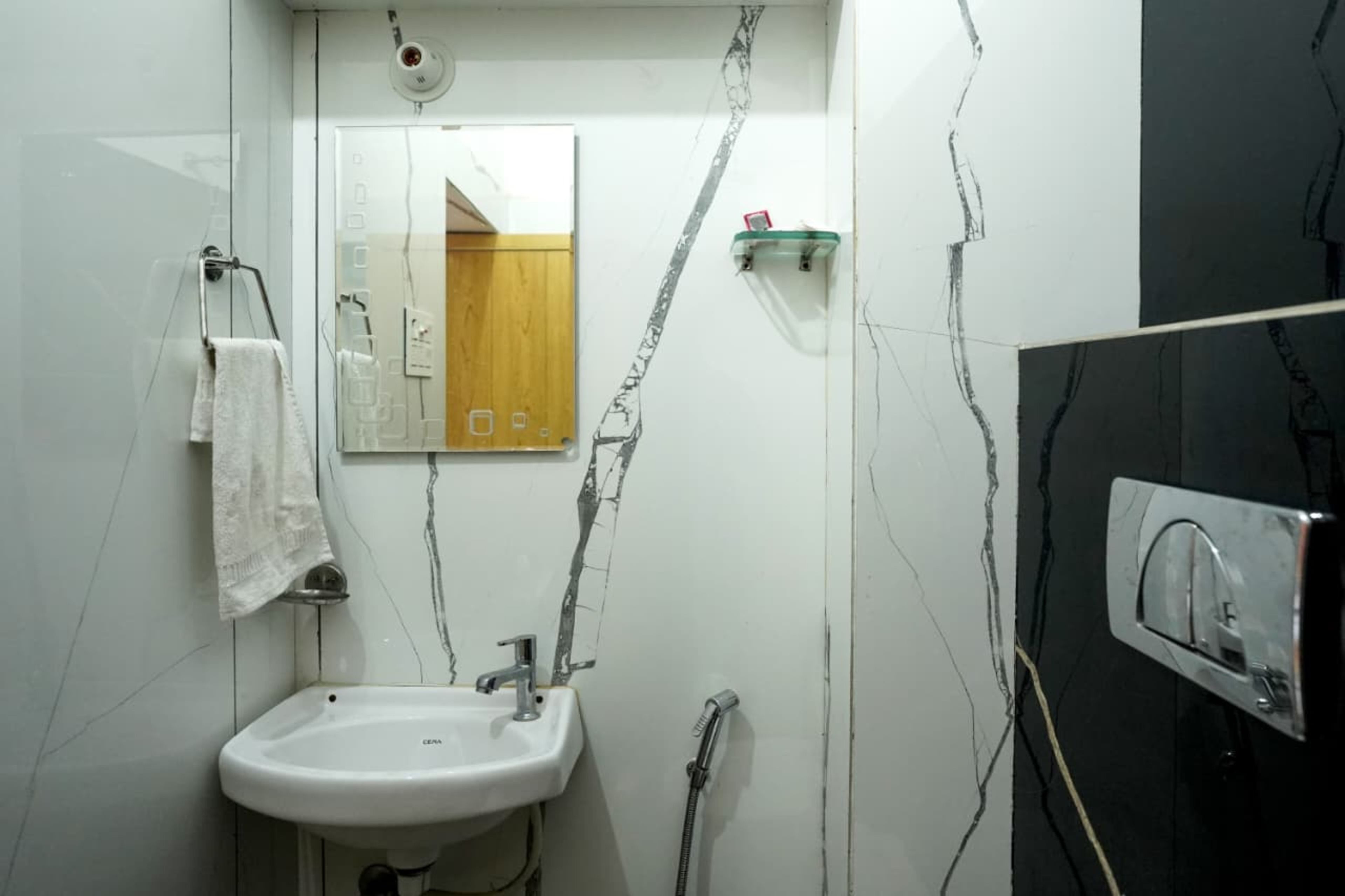 Une salle de bain avec un lavabo blanc, un miroir, une douche et un mur noir.