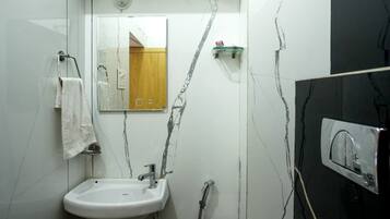 Une salle de bain avec un lavabo blanc, un miroir, une douche et un mur noir.