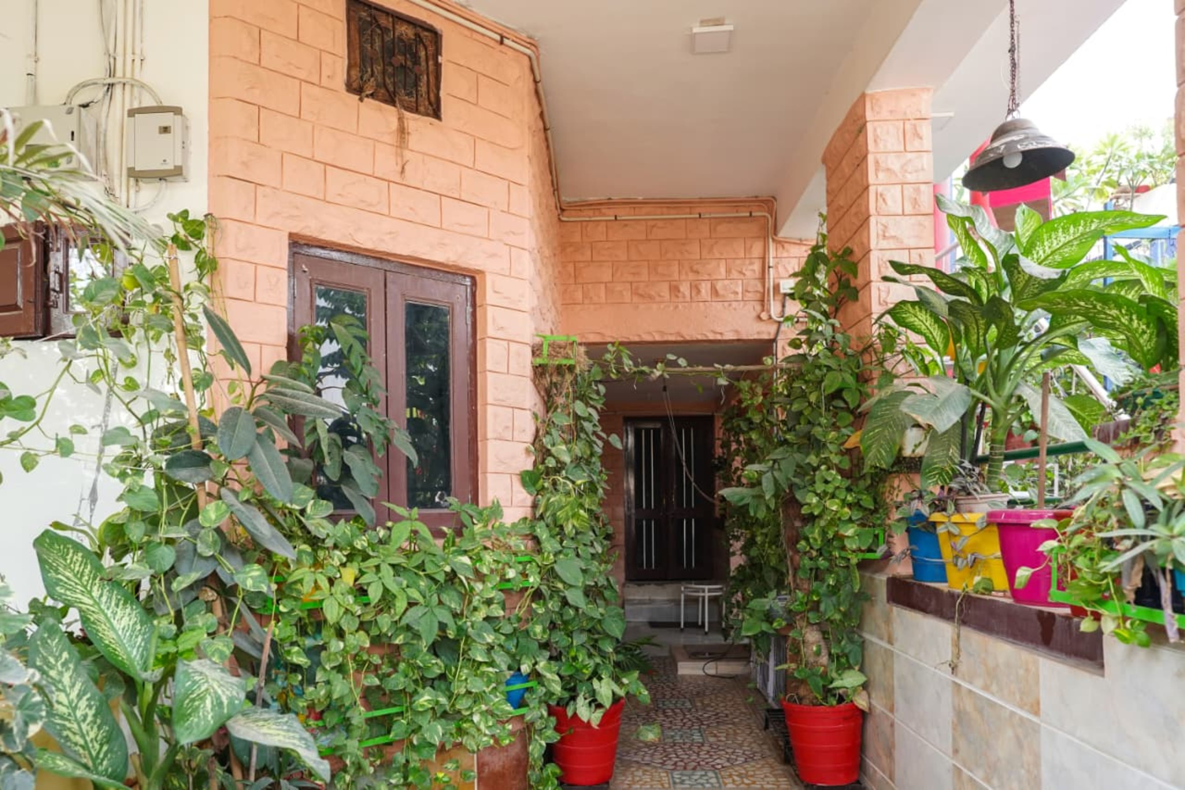 A narrow outdoor corridor with brick walls, potted plants, and a tiled floor.