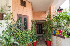 A narrow outdoor corridor with brick walls, potted plants, and a tiled floor. - Jannat Residency (Jodhpur)