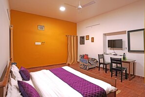 A hotel room with a bed, a desk with a chair, a television, and a window.