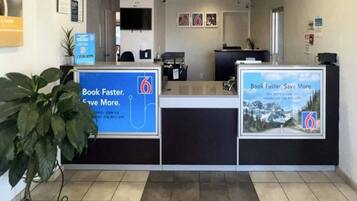 A reception area with a counter, a plant, and two informational posters.