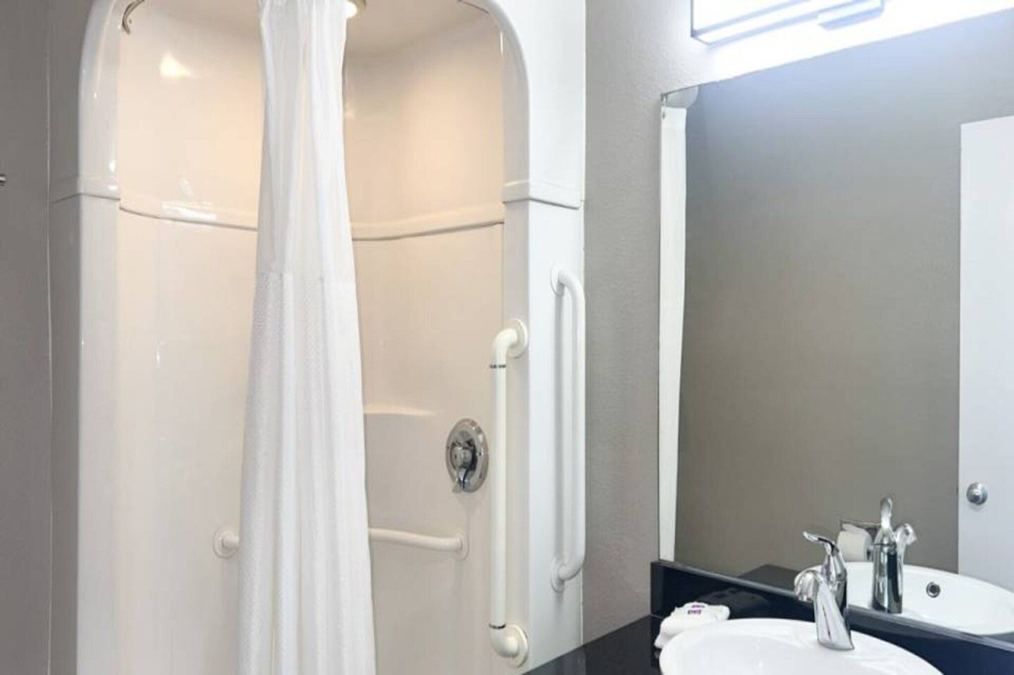A bathroom with a shower, a sink, and a mirror.