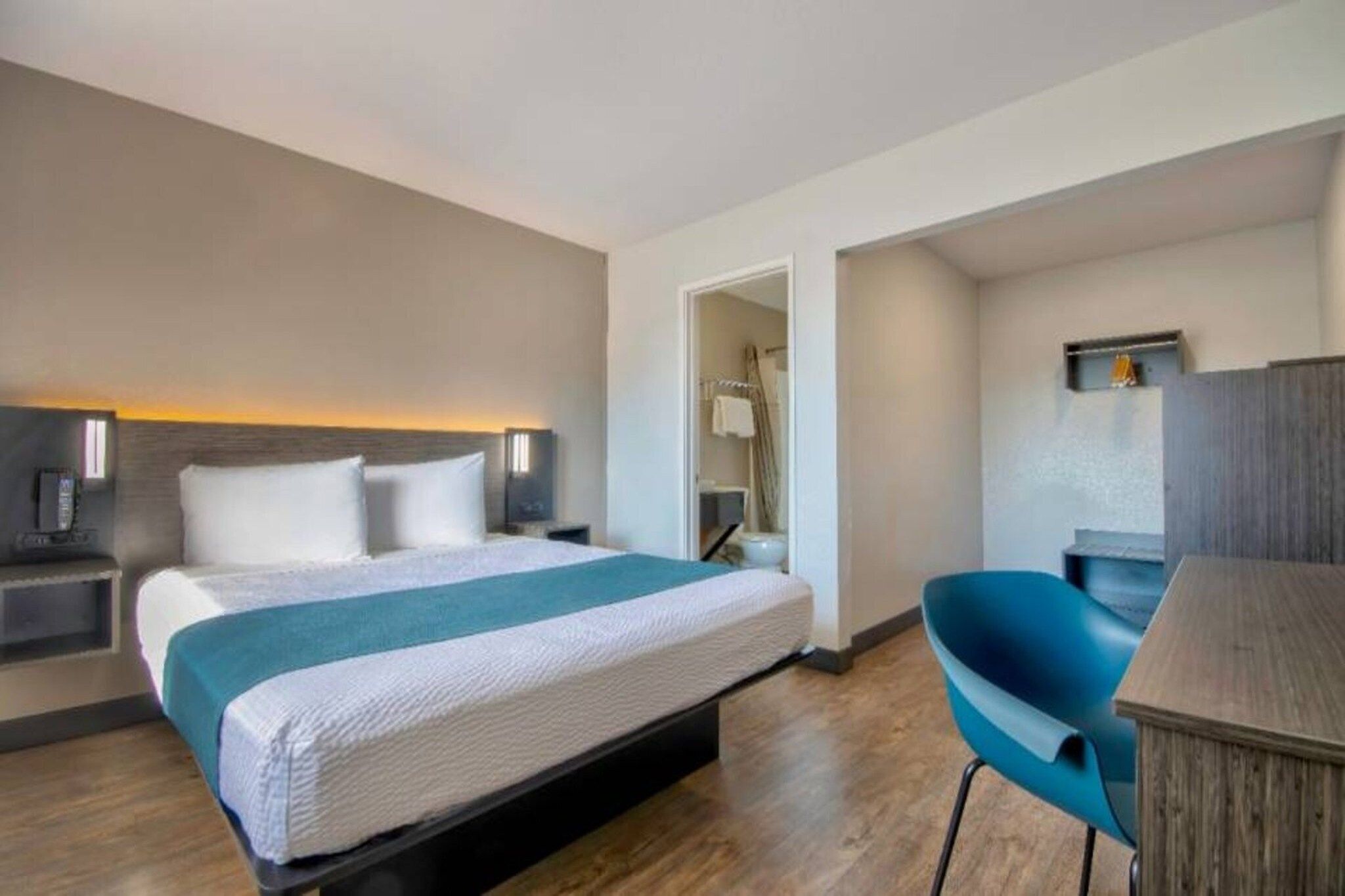 Een hotelkamer met een bed, nachtkastjes, een bureau en een stoel.