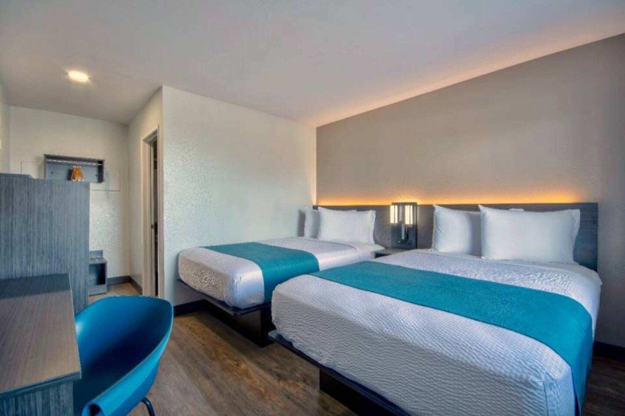 A hotel room with two beds, a desk, and a chair.