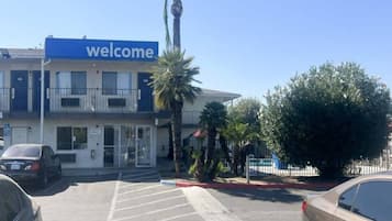 A building with a 'welcome' sign, a parking lot, and a palm tree.