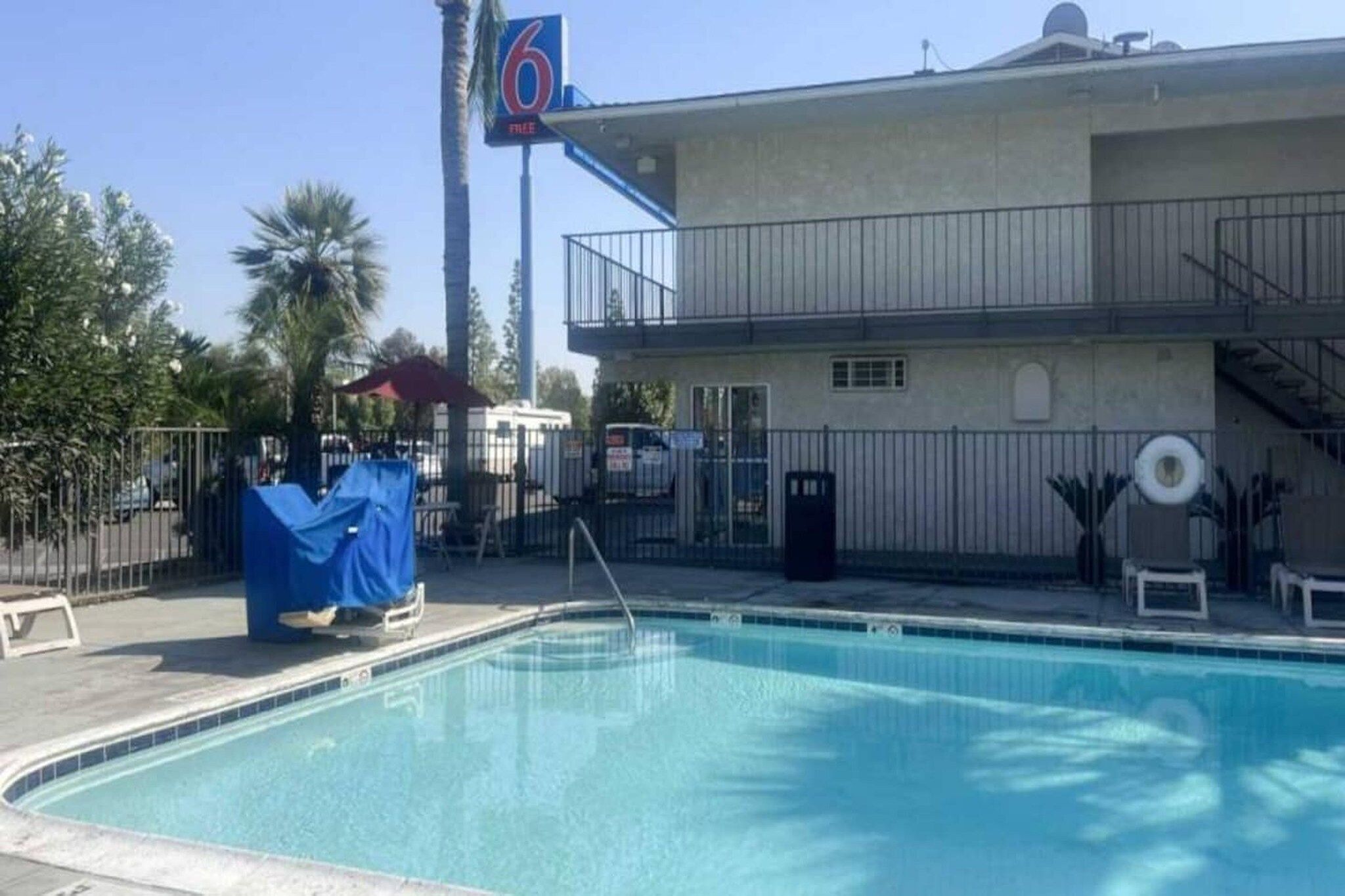 A swimming pool with a covered area, a building with a balcony, and a sign with the number 6.