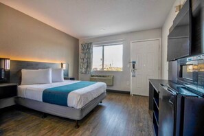 Habitación de hotel con cama, televisor, escritorio y ventana con vistas.
