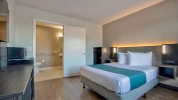 Et moderne hotelværelse med en stor seng, sengeborde, et skrivebord og et walk-in closet.