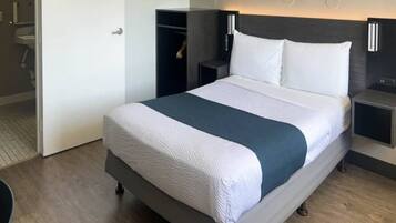 Een hotelkamer met een bed, nachtkastjes, een kledingkast en een badkamer.