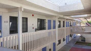 A motel with individual rooms, each with a door and window, and a covered walkway.