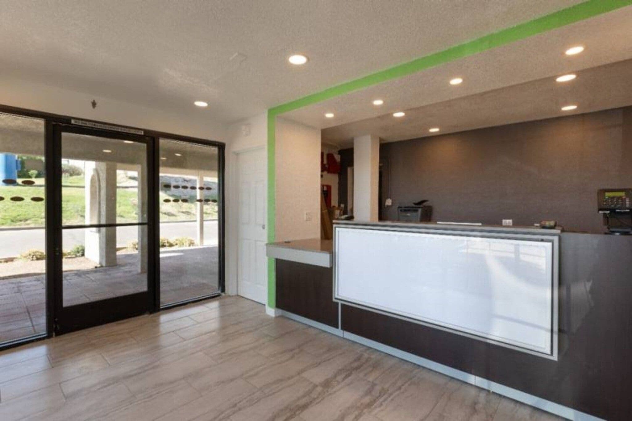 A reception area with a glass partition, a reception desk, and a view of the outdoors.