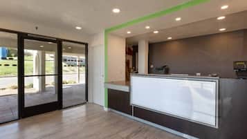 A reception area with a glass partition, a reception desk, and a view of the outdoors.