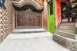 Una entrada tancada amb una reixa metàl·lica, escales que condueixen a una porta i una escala amb barana.