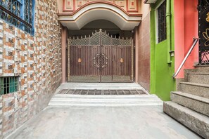 A gated entrance with a decorative metal gate, steps leading up to a building, and a wall with a patterned facade. - OYO Collection Jagannath Paradise (Varanasi)