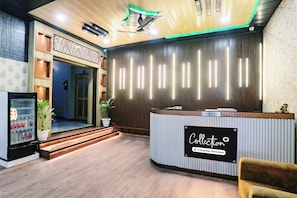 A reception area with a reception desk labeled 'Collection Company-Serviced,' a vending machine, and a staircase leading to an interior space. - OYO Collection Jagannath Paradise  (Varanasi)