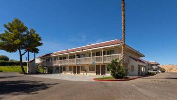 A two-story building with a balcony, a covered parking area, and a clear sky.