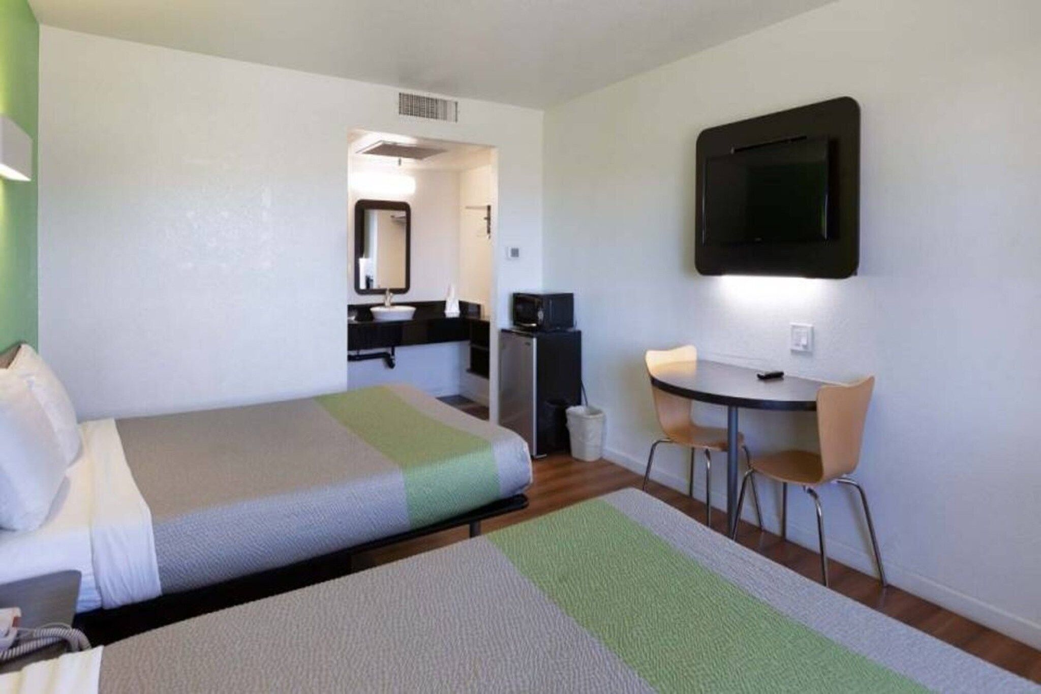 Habitación de hotel con cama, escritorio, silla, televisión y kitchenette.