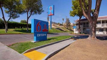 A motel sign with the number 6, a welcome sign, and a building entrance.