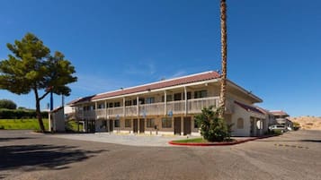 A two-story building with a balcony, a covered parking area, and a clear sky.