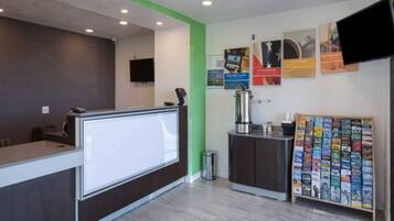 A reception area with a counter, a coffee machine, a trash bin, and a magazine rack.
