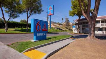 A motel sign with the number 6, a welcome sign, and a building entrance.