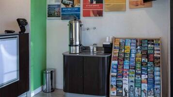 A reception area with a coffee machine, a magazine rack, and a desk with a phone.