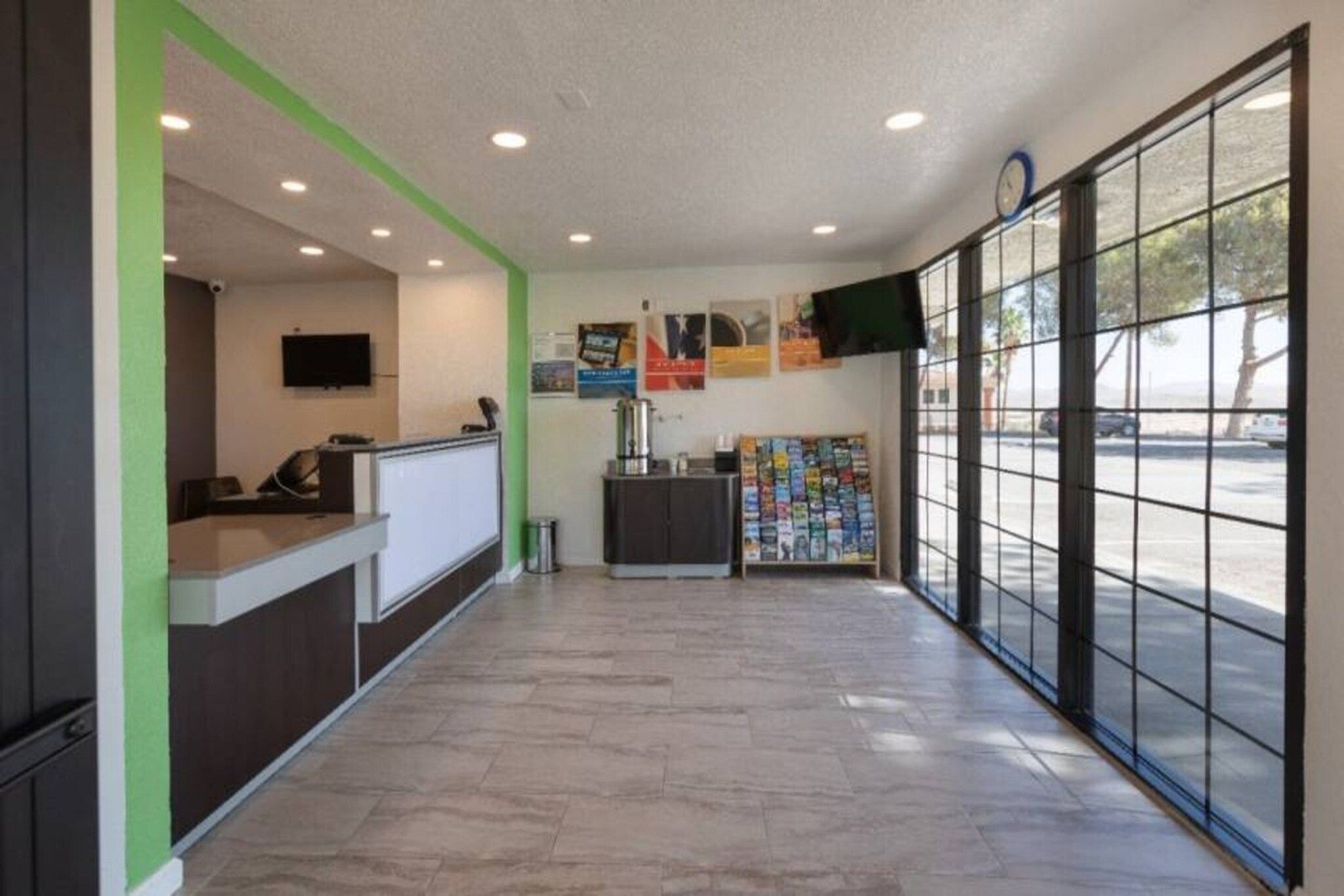 A reception area with a counter, a coffee machine, a bulletin board, and a large window with a view of the street.