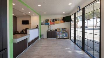 A reception area with a counter, a coffee machine, a bulletin board, and a large window with a view of the street.