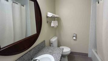 A bathroom with a sink, mirror, toilet, and shower.