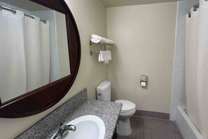 Une salle de bain équipée d’un lavabo, d’un miroir, de toilettes et d’une douche.