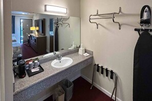 A hotel bathroom with a sink, mirror, towel rack, and a trash bin. - 1 King Bed|Mobility|Nsmk|Micfridg (Santa Ana)