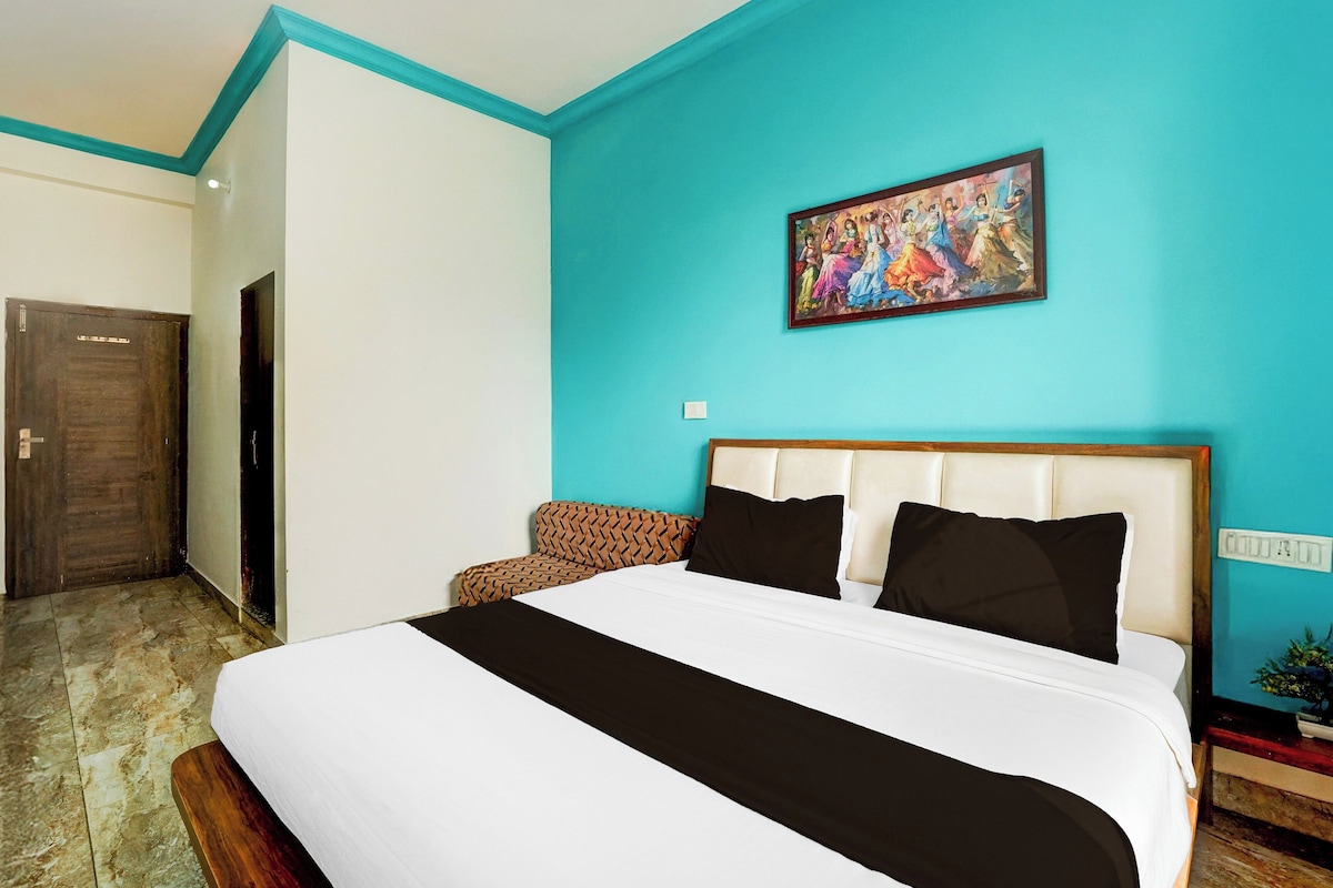A hotel room with a large bed, a headboard, a painting on the wall, and a door.