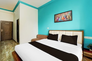 A hotel room with a large bed, a headboard, a painting on the wall, and a door. - Collection Salasar Balaji Formerly (Jaipur)