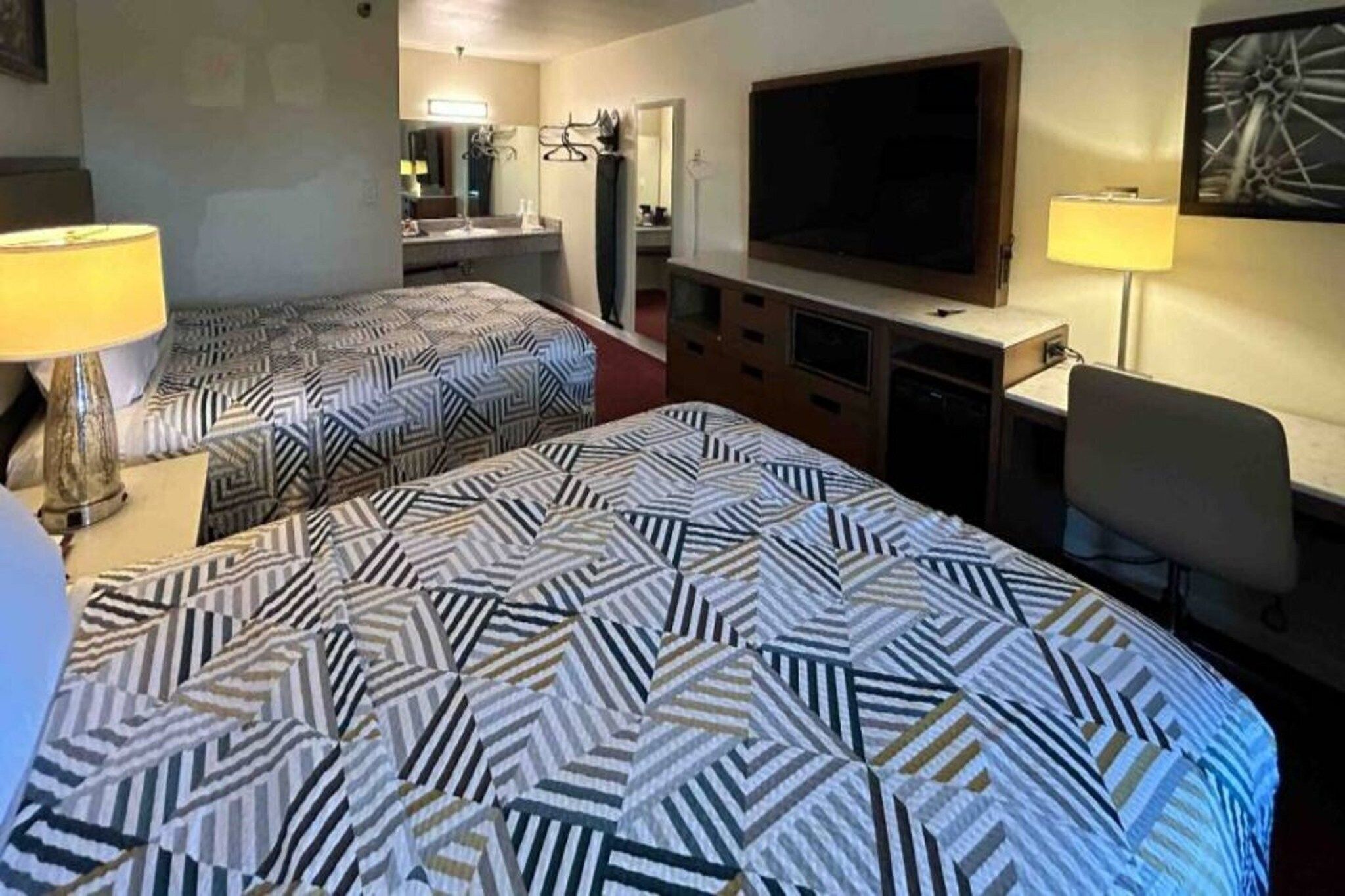 Ein Hotelzimmer mit zwei Betten, einem Fernseher, einem Schreibtisch und einem Sessel.