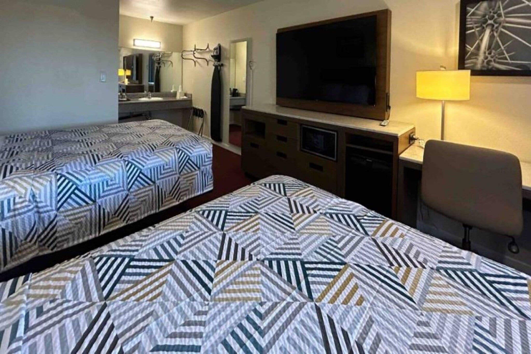 Habitación de hotel con dos camas, televisión, escritorio y una silla.