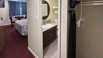 A hotel room with a bed, a bathroom with a sink, and a mirror.