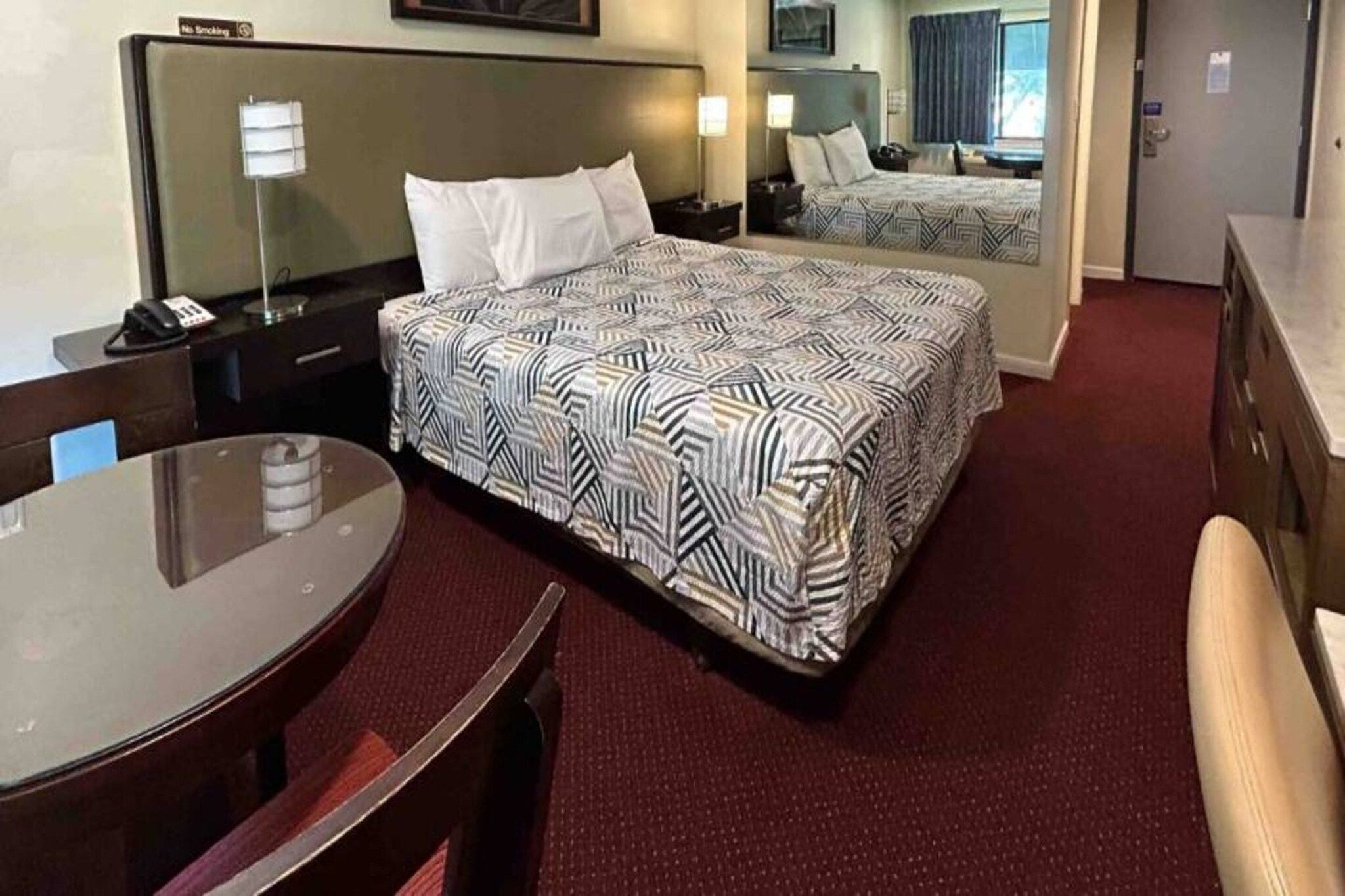 Ein Hotelzimmer mit Bett, Schreibtisch, Stuhl, rundem Tisch und Spiegel.