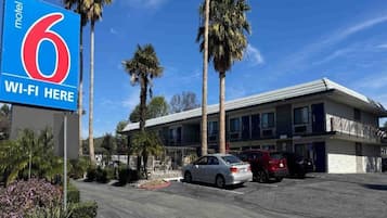 A motel with a sign indicating '6 Wi-Fi Here' and a parking lot with several cars.