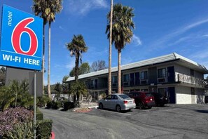 Ein Motel mit einem Schild, das '6 WLAN hier' anzeigt, und einem Parkplatz mit mehreren Autos.